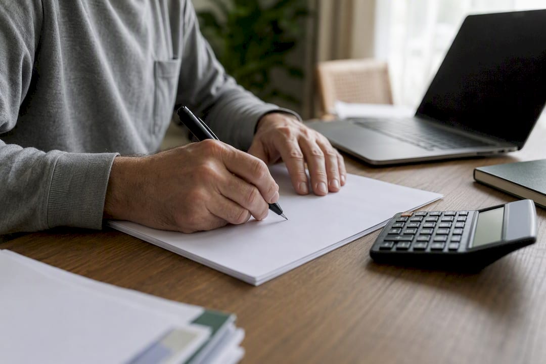Hands correcting tax form with calculator nearby